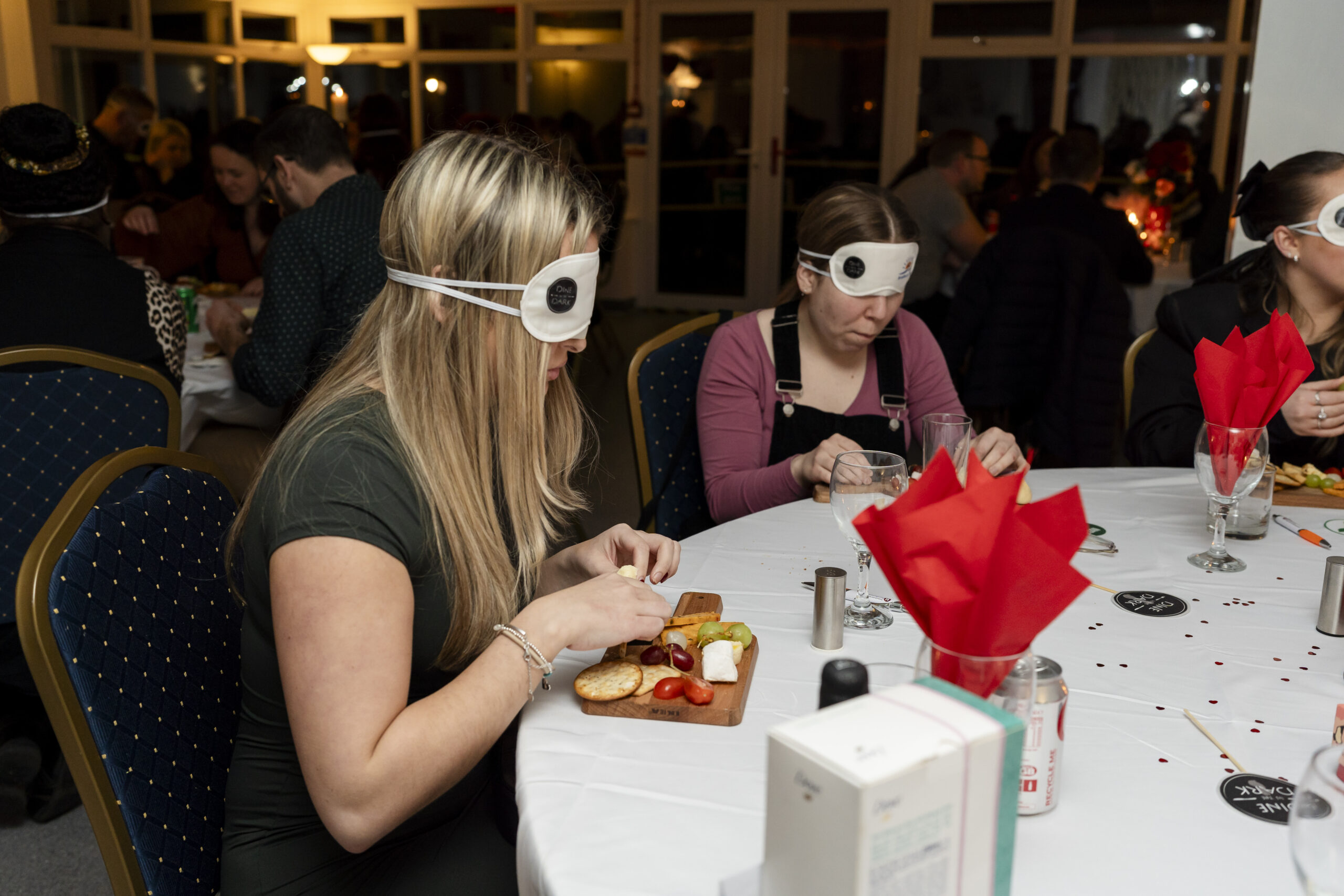 http://Two%20people%20sat%20at%20a%20table%20wearing%20blindfolds%20and%20eating%20from%20cheese%20boards.