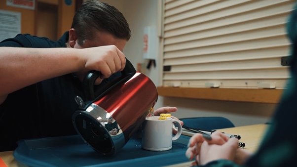 http://A%20man%20carefully%20pours%20hot%20water%20from%20a%20red%20kettle%20into%20a%20mug%20during%20an%20independent%20living%20skills%20activity.